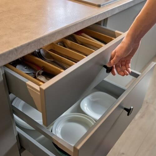 a person opening an aluminium kitchen cabinet drawer